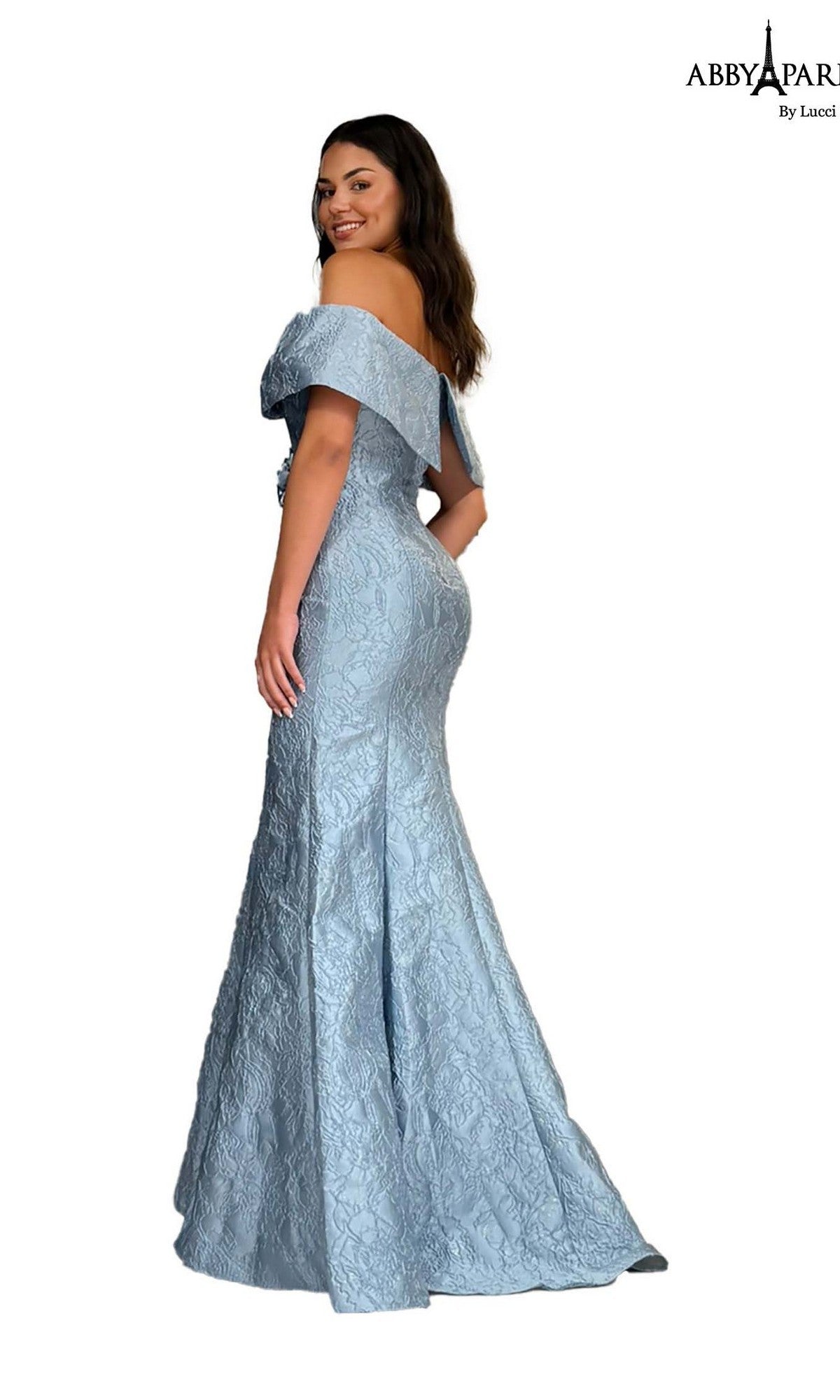 A woman poses in the Abby Paris 96087, a light blue, off-the-shoulder, floor-length prom dress with a textured brocade pattern.